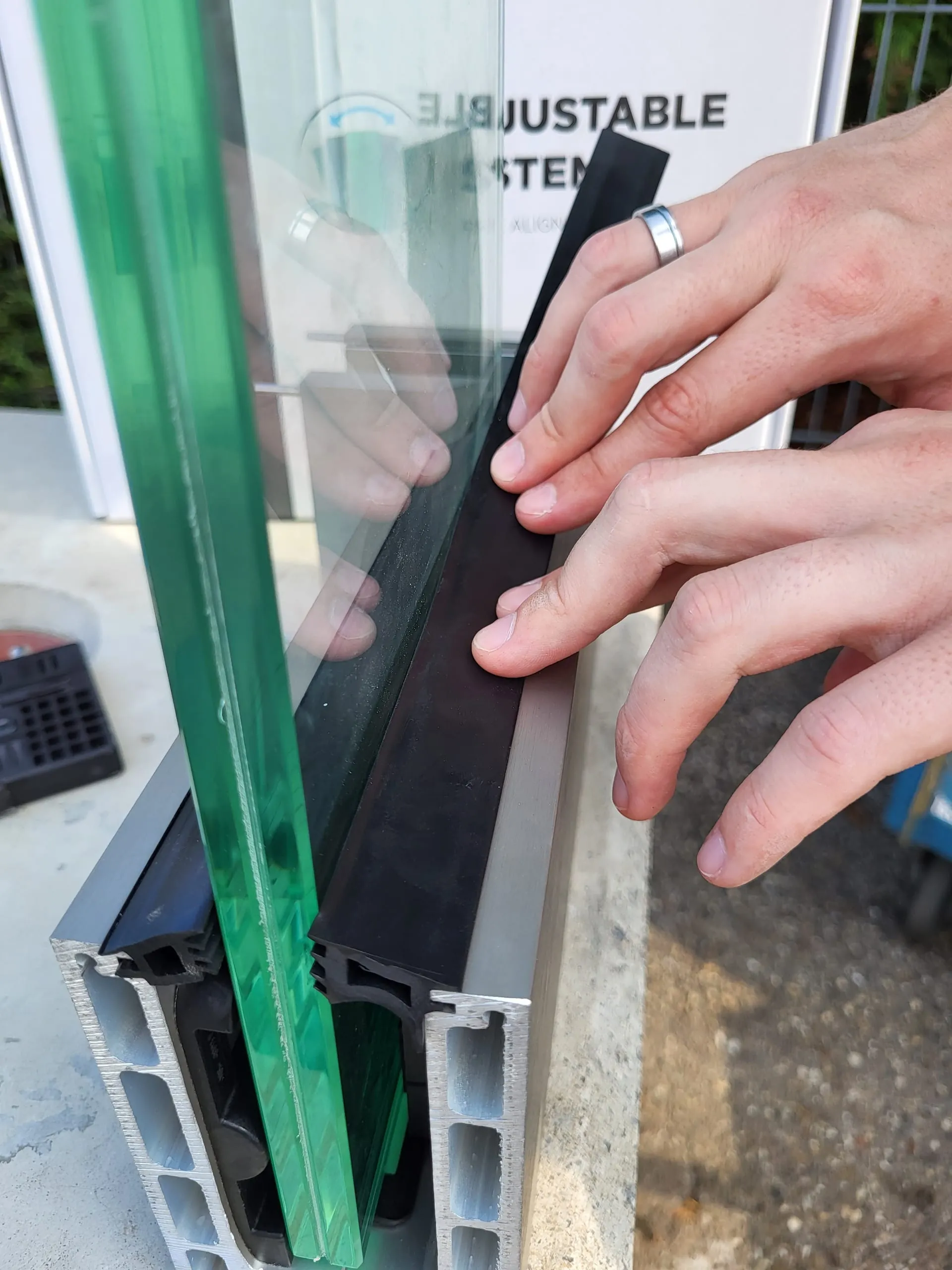 5. Schritt: Nachdem Sie die Glasscheibe lotrecht ausgerichtet haben, drücken Sie das Universalgummi an der Vorderseite in die entsprechende Nut an der Bodenschiene ein.