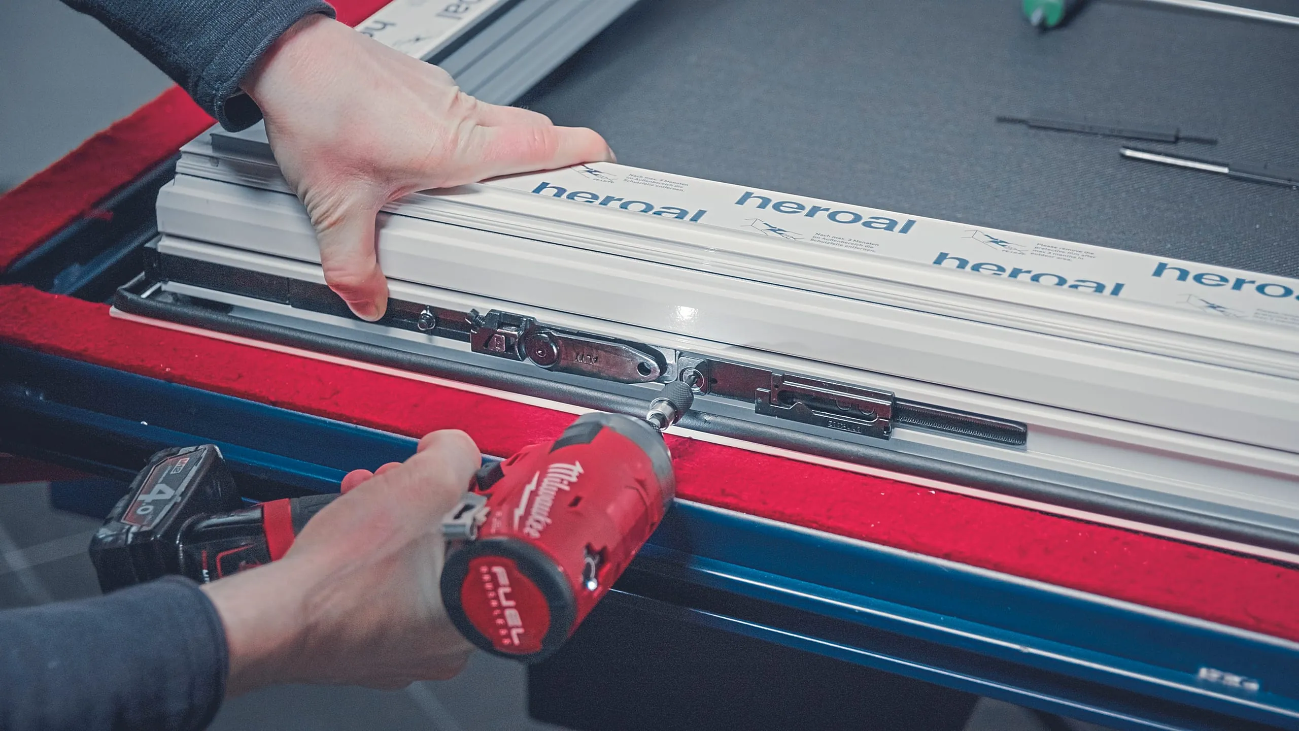 4. Schritt: Legen Sie die Eckumlenkung an der Bandseite des Flügels in die Beschlagsnut ein, drücken Sie die Sicherungskappe an und verriegeln Sie die Fixierschraube. Dann koppeln Sie die Oberschiene an die Eckumlenkung an und drehen die Sicherungsschraube ein.