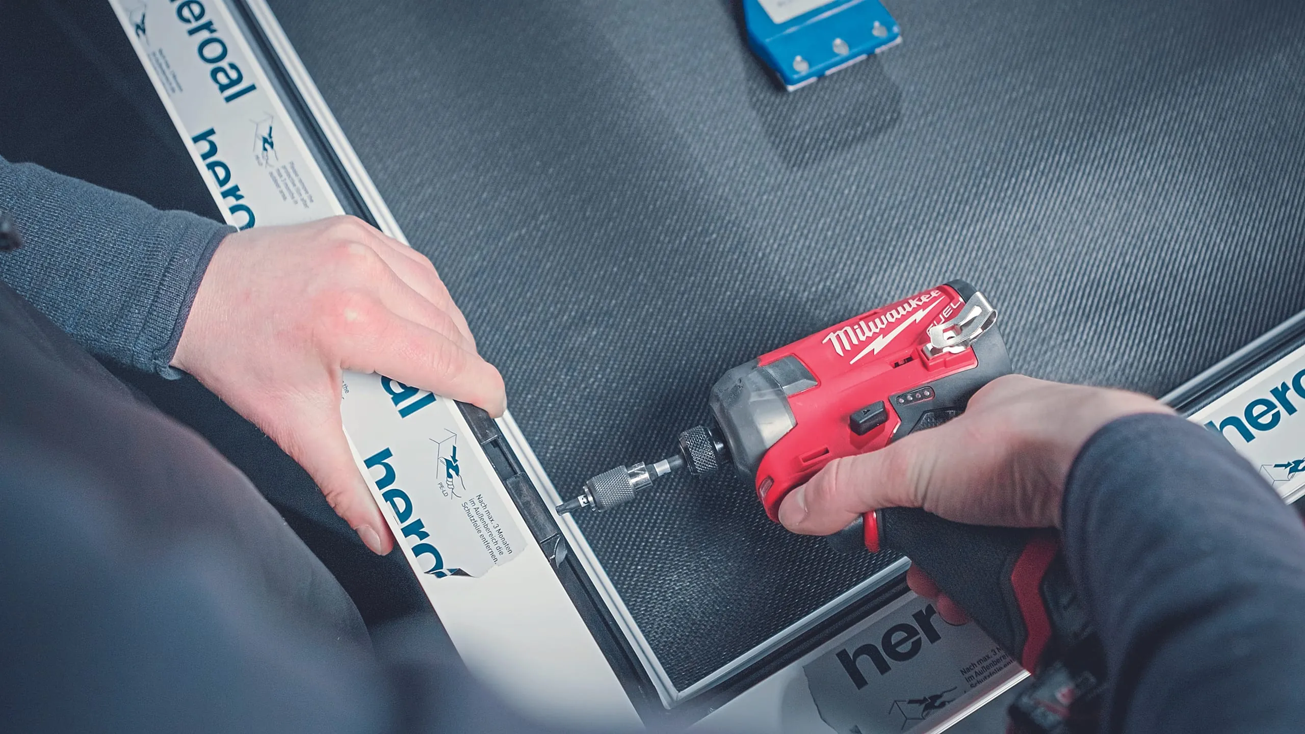 6. Schritt: Legen Sie die Schließbleche an den zuvor ermittelten Positionen in die Beschlagsnut ein und schrauben Sie sie mit dem Akkuschrauber fest. Schwenken Sie die Schere und das untere Ecklager ein und befestigen Sie die Bauteile ebenfalls mit dem Akkuschrauber.