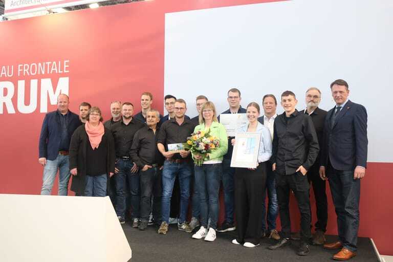 Firmenausflug nach Nürnberg: Inhaberfamilie und Mitarbeiter auf der Bühne der Preisverleihung, ganz rechts Laudator Dr. Johann Quatmann von der TSG GmbH.