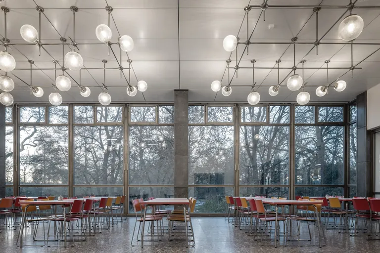 Das ikonische Stabwerksystem mit den Kugelleuchten konnte in gro&szlig;en Teilen erhalten werden, ebenso die Betonwerksteinb&ouml;den im gesamten Haus.