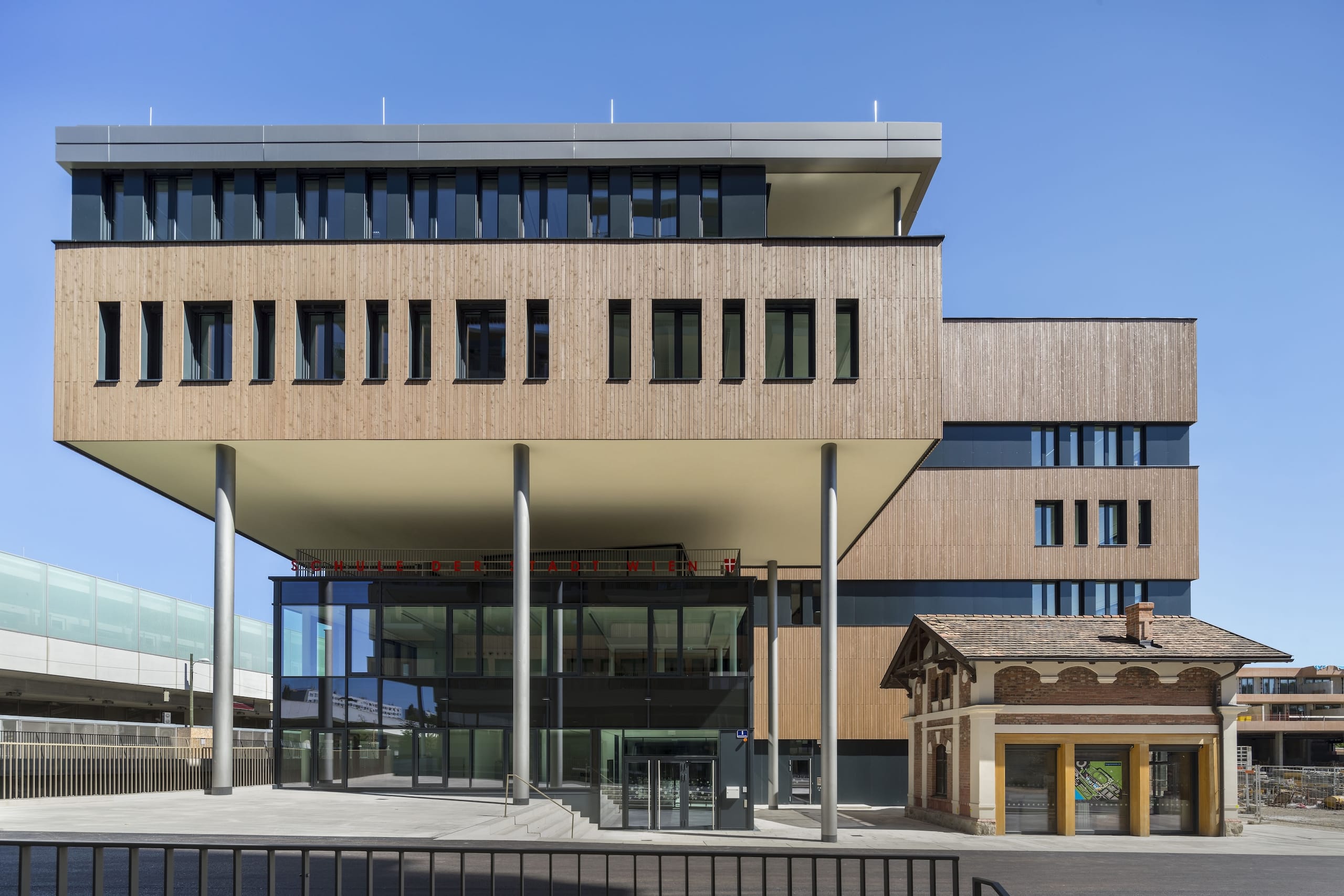 Analog zum Fassadenentwurf des Nachbargebäudes Korso spielen am Schulhaus Kontraste und geometrische Formen eine wesentliche Rolle. So wechseln sich in Holz gefasste, leicht auskragende Riegel mit dunklen Fugengeschossen ab, was die Wahrnehmung der Geschossanzahl scheinbar halbiert. Am Korso noch aus Brandschutzgründen in farblich ähnliche Keramikelemente gerahmt, sind die riegelartigen Geschosse am Schulgebäude mit vorpatiniertem Lärchenholz bekleidet.