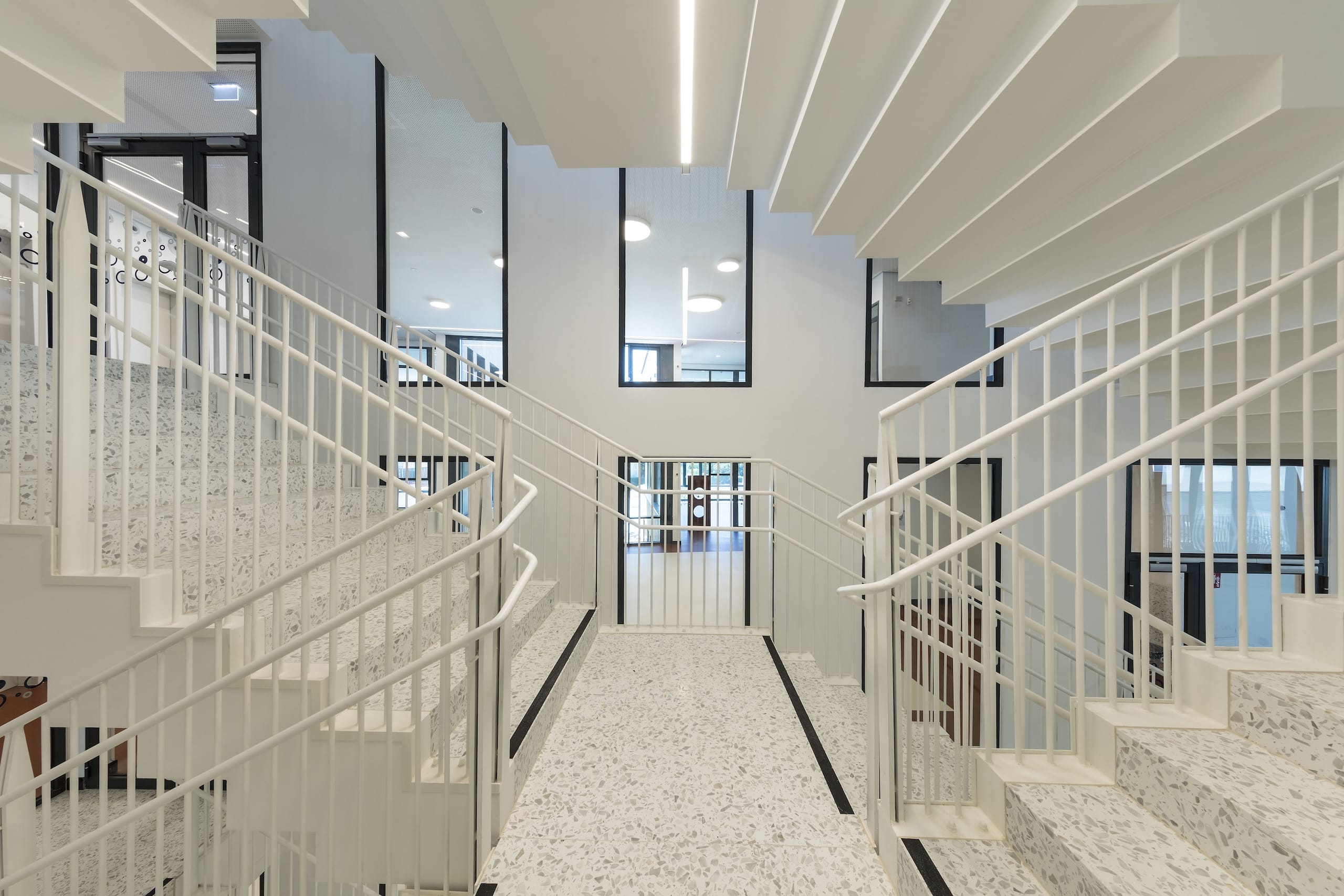 Zum Treppenhaus reihen sich hohe Verglasungen zu einer inneren Fassade und sorgen für Lichteinfall in die hell gestalteten Räume. Zum Einsatz kamen flächenbündige Elemente Forster Presto, die sich für Raumabschlüsse ohne besondere Anforderungen an den Wärmeschutz eignen.