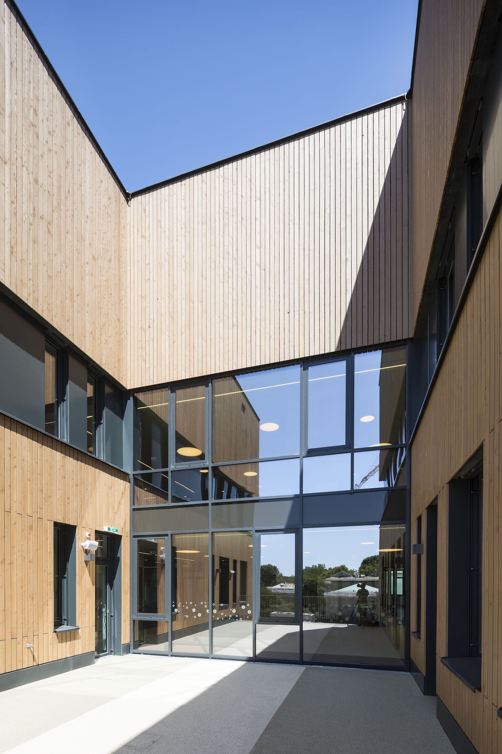 Die eingerückten Fugengeschosse sind als Pfosten-Riegel-Konstruktion ausgeführt. Die Fassadenprofile Forster Thermfix Vario El90 in der Farbe Anthrazit bilden gemeinsam mit den Fenstern eine homogene Fläche und dadurch die gewünschte Abstufung zum Holz. Mit dieser Konstruktion konnten sowohl Sektionen mit, als auch ohne brandschutztechnischen Anforderungen in einer Fläche überbrückt werden. Schlanke Ansichten kennzeichnen die Elemente aus pulverbeschichtetem Stahl, in die transparente ebenso wie opake Füllungen eingesetzt wurden.