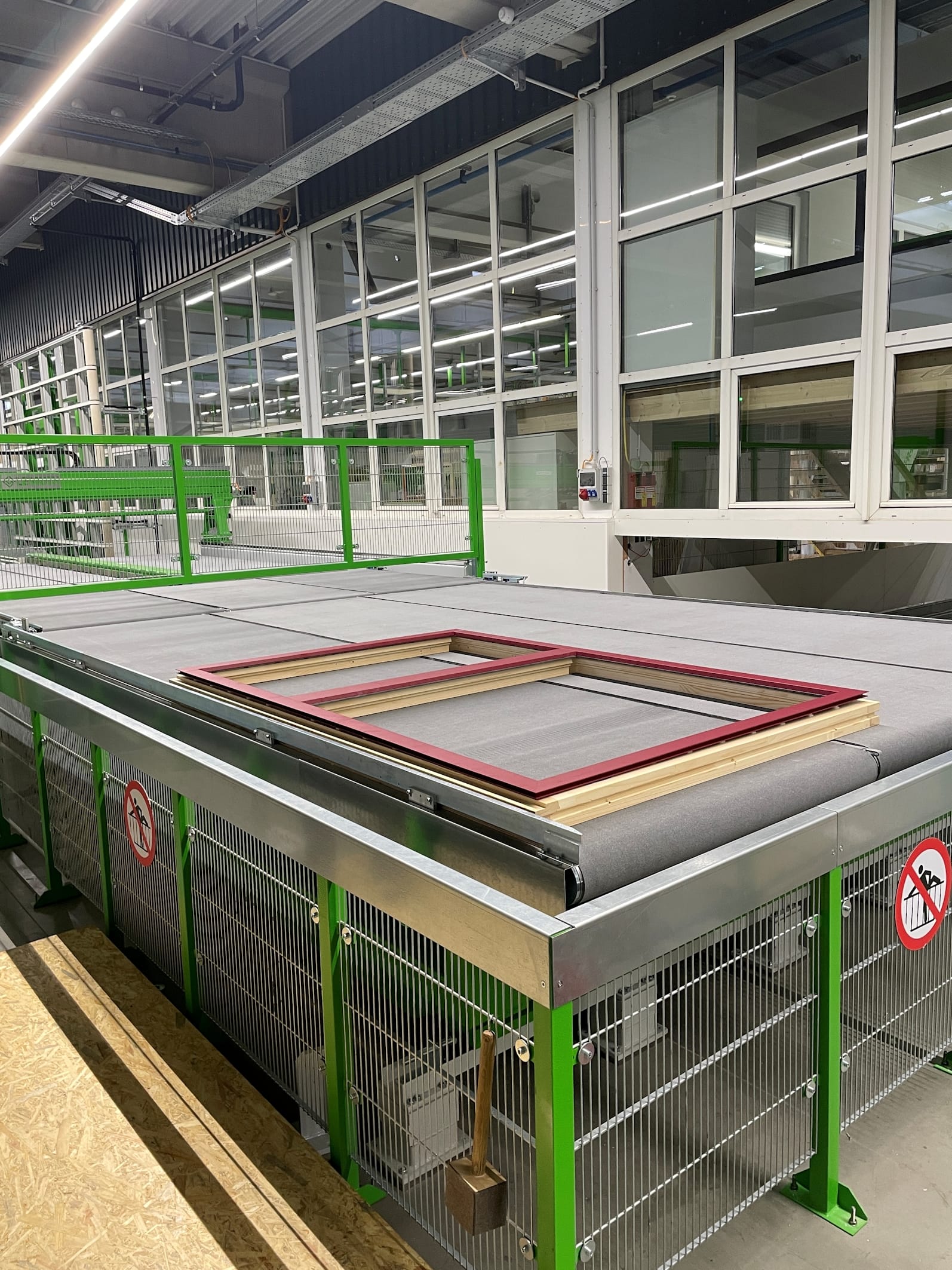 Passgenau vorbereitet: Vorgefertigte Aluschalen werden automatisch zugeführt, händisch am Auflageplatz auf den Rahmen gelegt und an einer Ecke sicher fixiert. Anschließend gelangt er automatisch zur Wendestation, die den Rahmen von der Innenseite auf die Außenseite dreht.