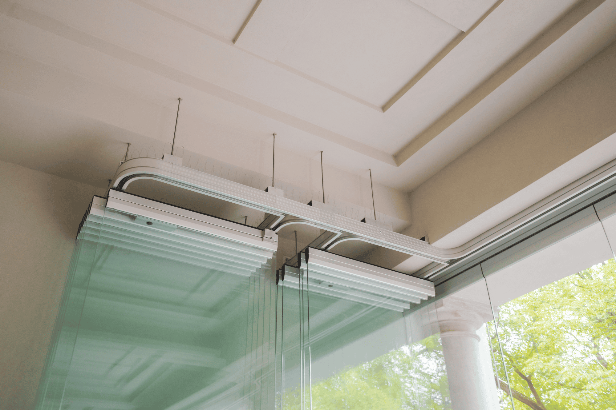 Für das Betonhaus setzte Geze eine spezielle Lösung um: Drei der Paneele des MSW-Systems sind so konstruiert, dass sie gleichzeitig als Eingangstüren dienen. Wenn das Stellwandsystem geöffnet oder geschlossen wird, bewegen sich diese integrierten Türelemente zusammen mit dem Rest des Systems. Das erhalte ein nahtloses Erscheinungsbild und ermögliche einen einfachen und funktionalen Zugang zum Gebäude. In Zusammenarbeit mit einem Statiker von SQT Inżynieria w Budownictwie und einem Architekten von Jems Architekci wurde außerdem eine Stahlunterkonstruktion zur Verstärkung der bestehenden Decke entworfen.
