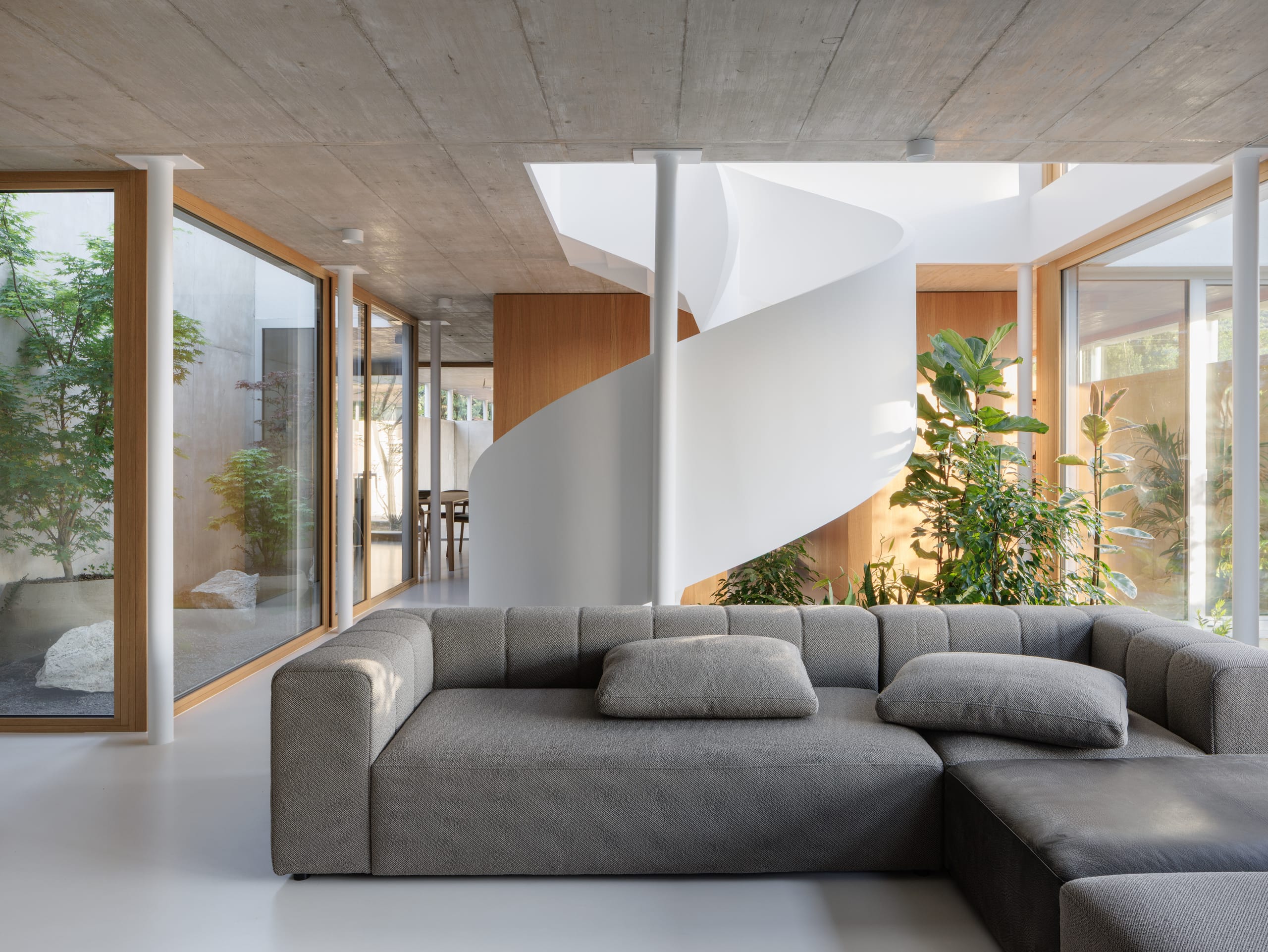 Große Verglasungen und sorgfältig inszenierte Sichtachsen sollen beim „Haus mit Ring" einen ununterbrochenen visuellen Dialog mit dem Garten schaffen. Die Fenster sollen als zentrales architektonisches Werkzeug den Innen- und Außenraum miteinander verbinden und natürliches Licht als aktives Gestaltungsmaterial nutzen. Durch die durchgehenden Glasflächen werde außerdem ein schwebender Effekt des Obergeschosses erzielt. Stahlstützen verbinden sich dabei nahtlos mit den Verglasungsflächen.